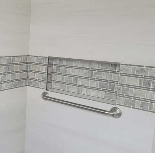 Long horizontal stainless grab bar below a tiled niche