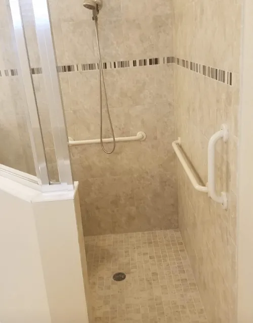Two white grab bars in a beige walk-in shower